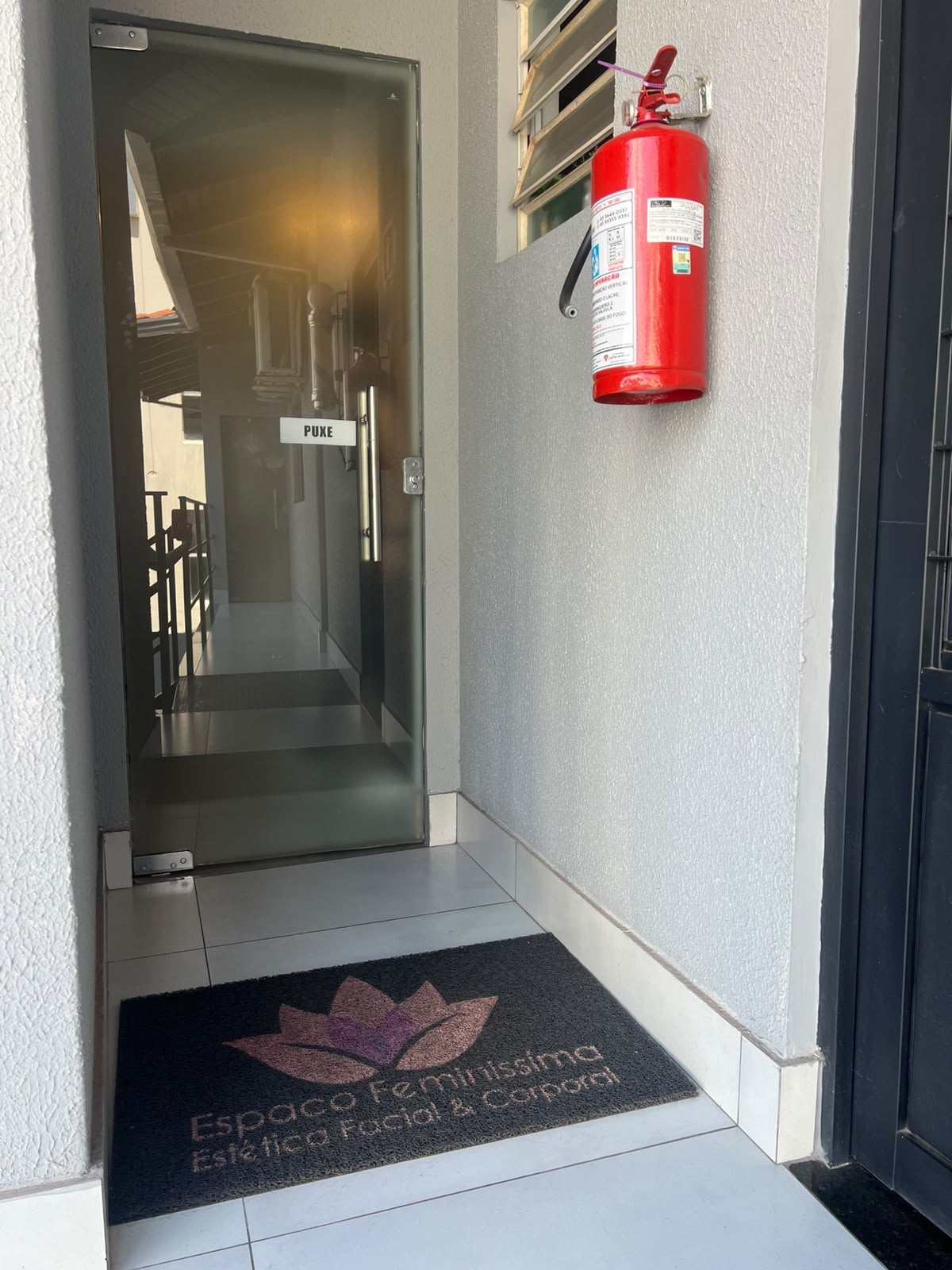 Entrada do Espaço Feminíssima, com porta de vidro e tapete com a marca